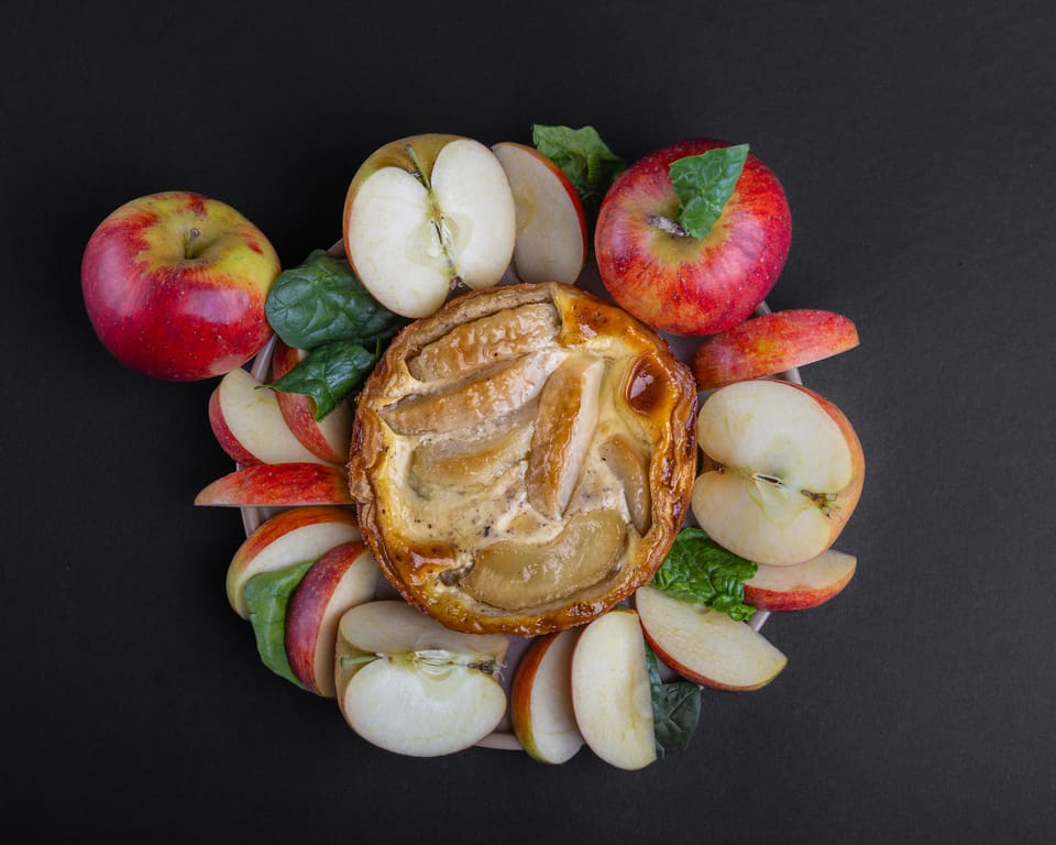 Apfelkuchen, umgeben von frischen Äpfeln und Apfelschnitzen