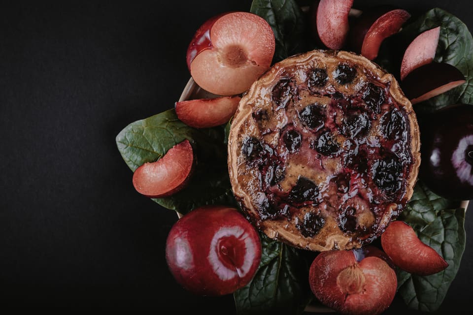 Zwetschgenkuchen, umgeben von frischen Zwetschgen und Blättern