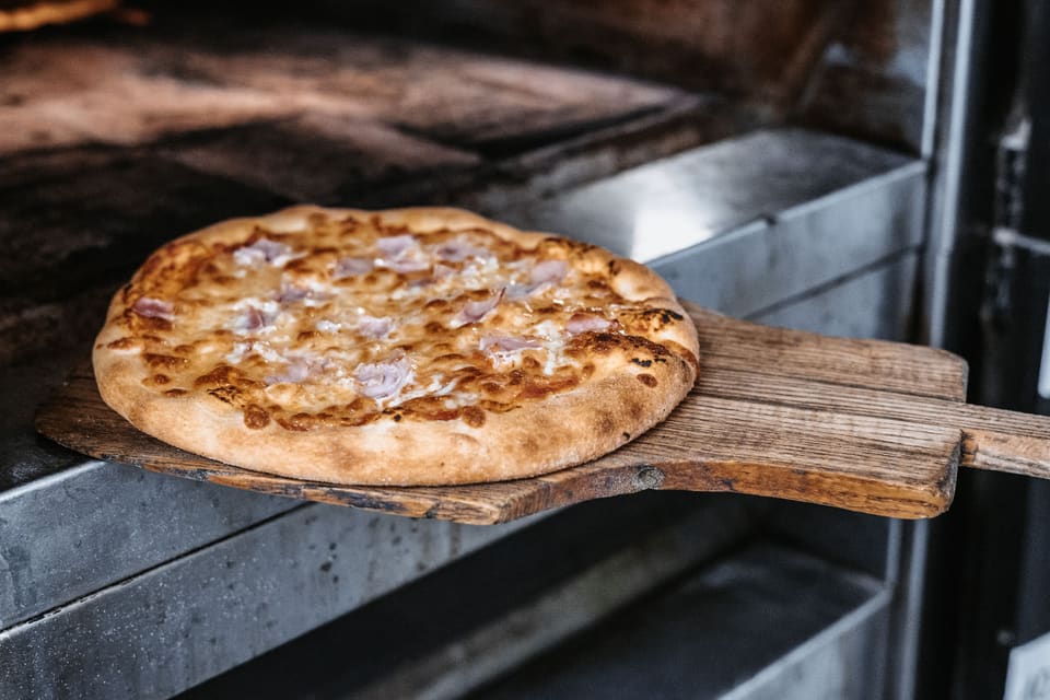 Pizza auf einem Holzschieber vor dem Ofen