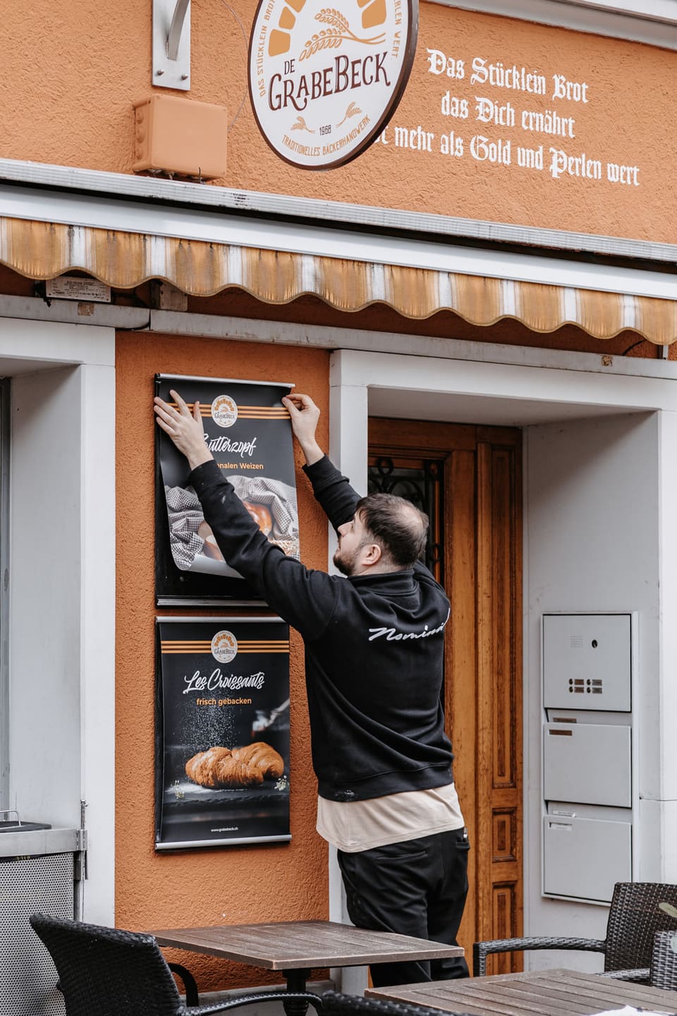 Ein Mitarbeiter hängt ein Plakat an der Eingangstür auf