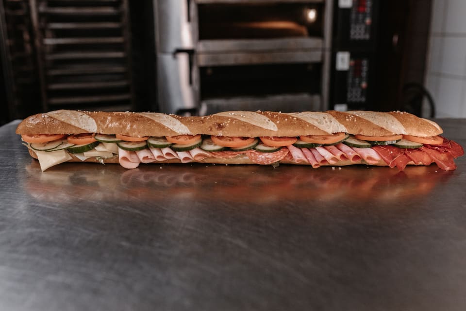 Langes Sandwich mit Schinken, Gurke und Tomate auf der Arbeitsfläche