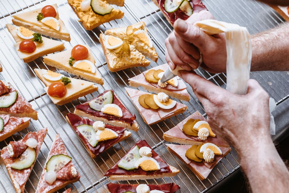 Frisch belegte Canapés mit Ei, Tomate und Gurke werden in der Backstube garniert