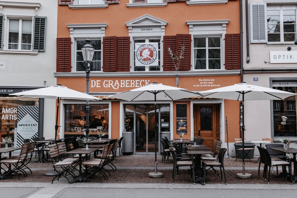 Die Fassade von de GrabeBeck mit Sonnenschirmen und Tischen im Freien
