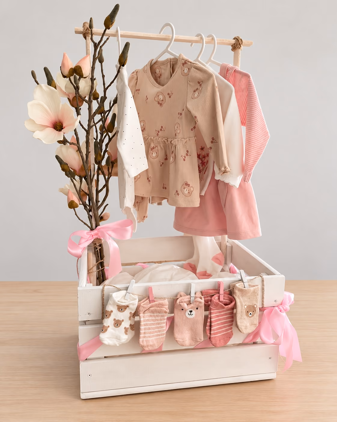 Babyshower-Kiste mit Babysocken und Babykleidern an einer Kleiderstange