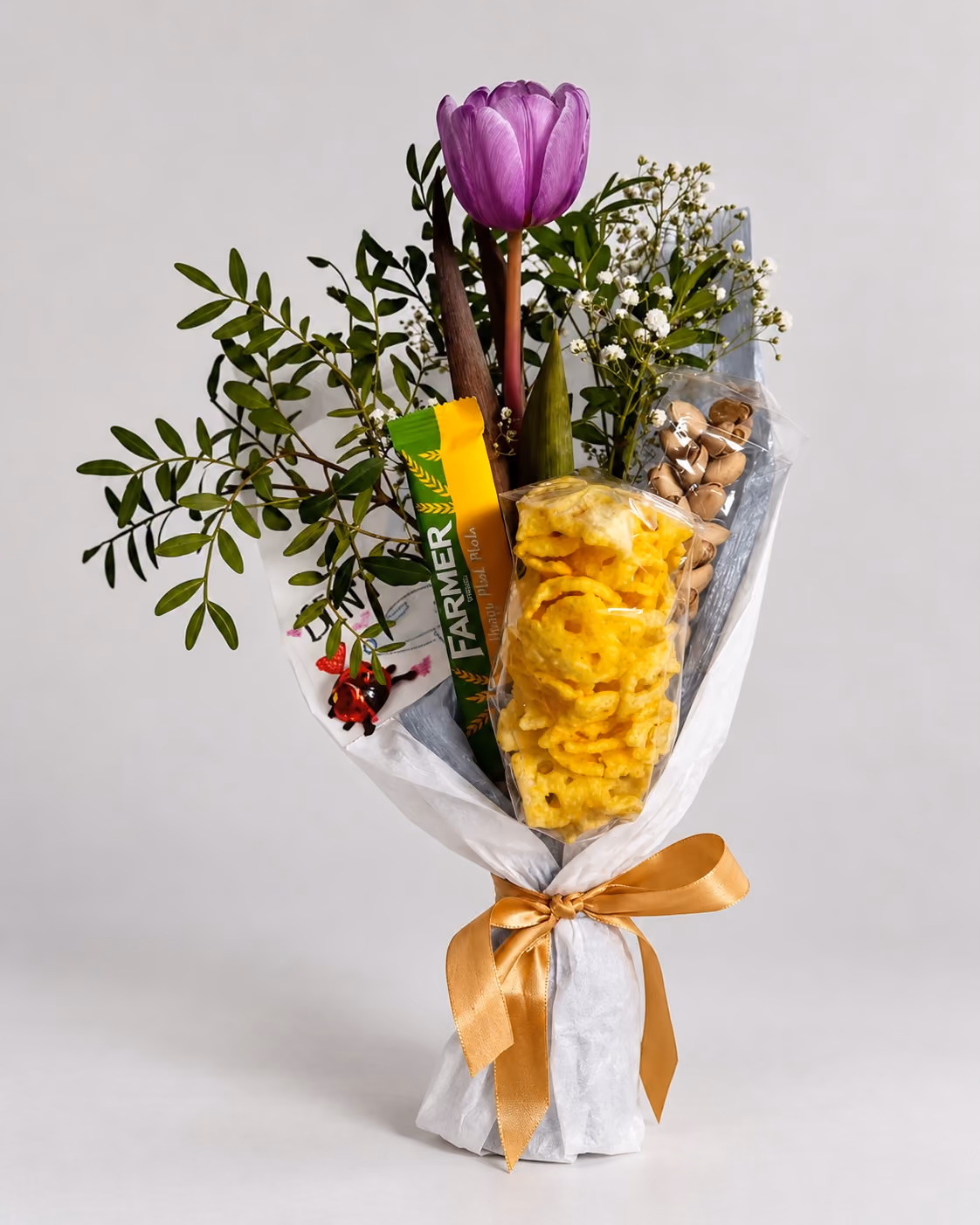 Bouquet mit lila Tulpe, Grün, Pistazien, Chips und Riegel, gebunden mit goldener Schleife